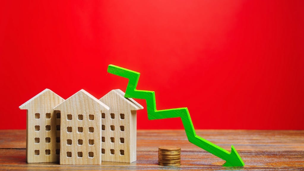 Green arrow pointing down next to wooden model home indicates a fall in home prices