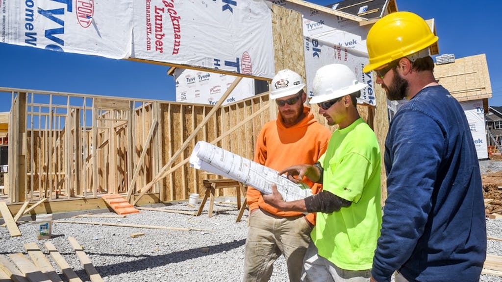 Three home builders look over plans at a jobsite