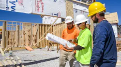 Three home builders look over plans at a jobsite