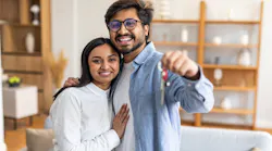Millennial couple holds up keys to newly purchased home