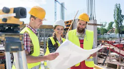 A group of three young construction workers at a jobsite together A group of three young construction workers at a jobsite together