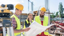 A group of three young construction workers at a jobsite together A group of three young construction workers at a jobsite together