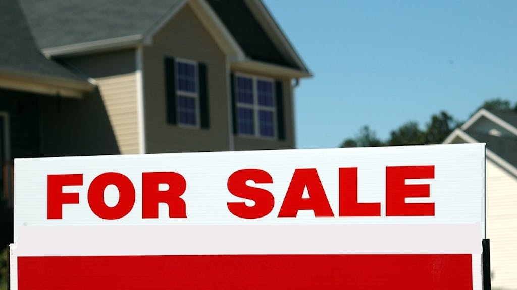 A home with a 'For Sale' sign in the front yard