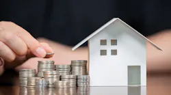 Stacking coins next to a model home, indicating high levels of home equity