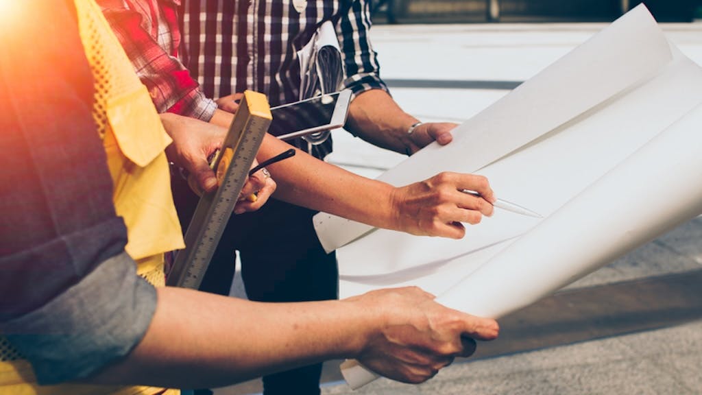 A construction worker receives training from a coworker