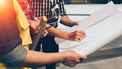 A construction worker receives training from a coworker A construction worker receives training from a coworker