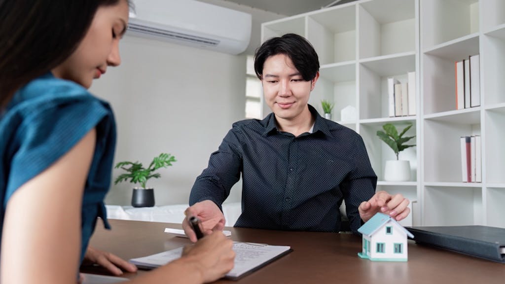 Homebuyer signs papers with a real estate agent