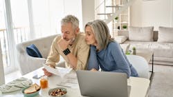 Older couple goes over finances at their kitchen table Older couple goes over finances at their kitchen table