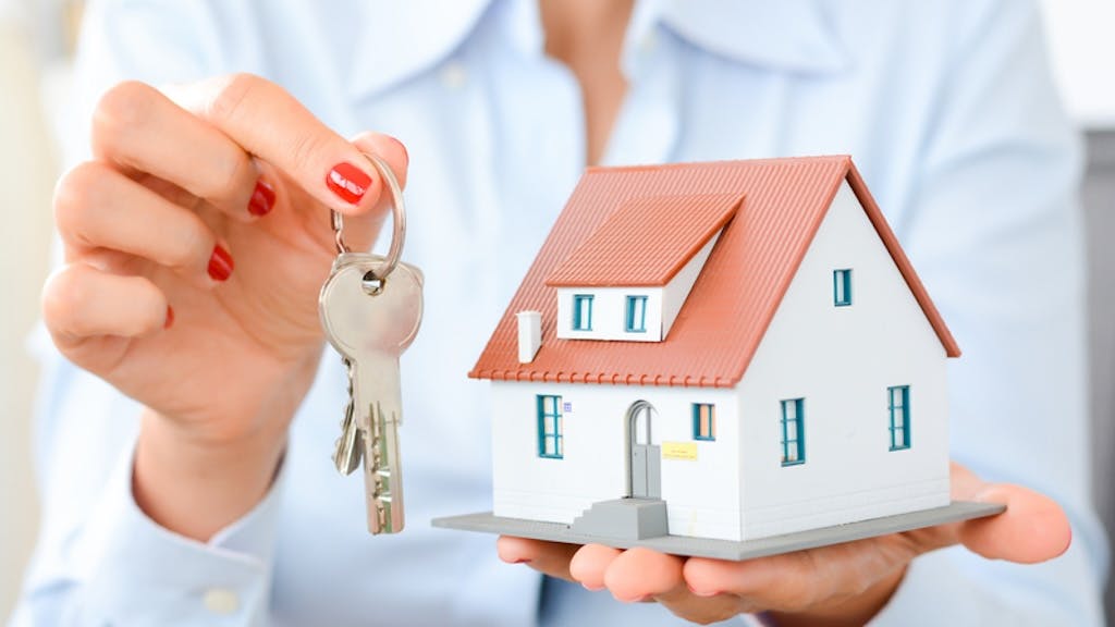 Real estate agent holding up model home and house key