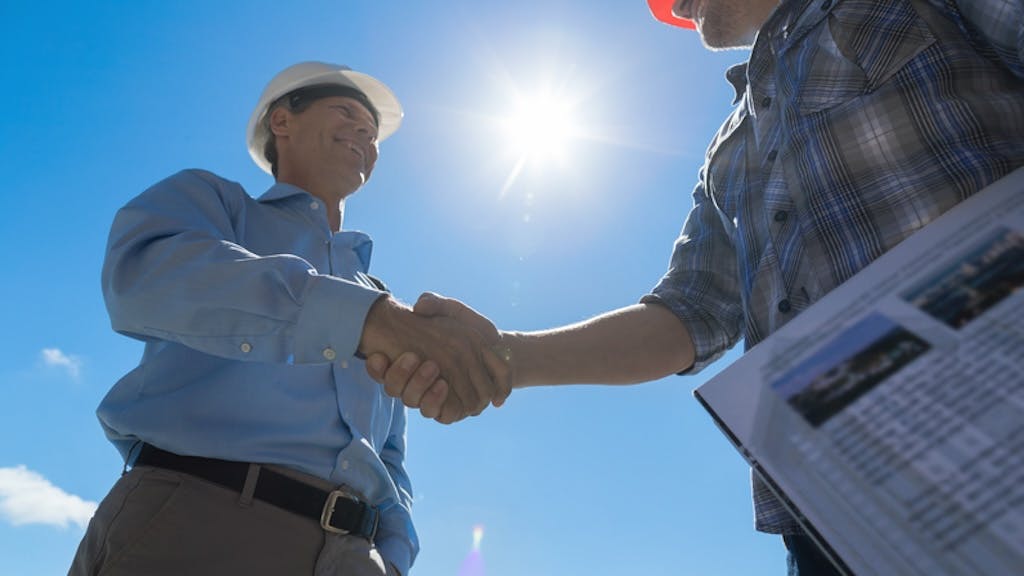 Two construction workers shake hands