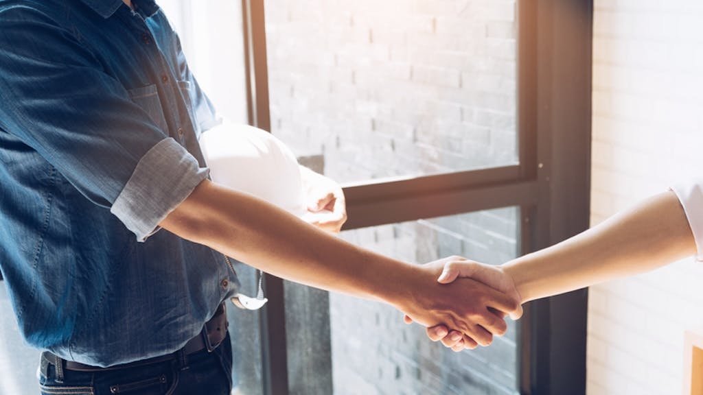 Construction worker shakes hands with employer after being hired