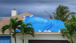 Roof of home covered with tarp after being damaged in hurricane Roof of home covered with tarp after being damaged in hurricane