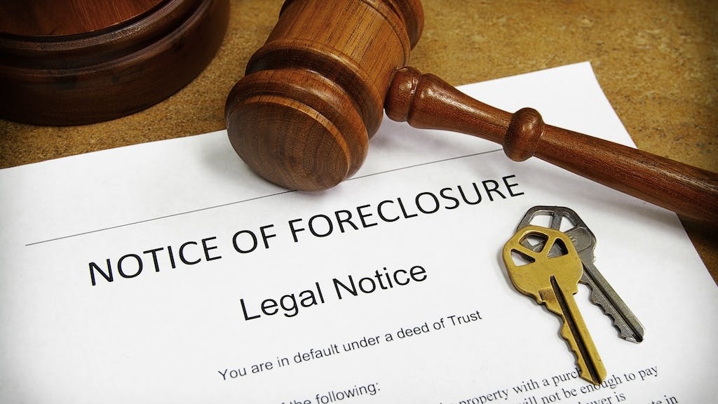 Foreclosure filing sitting on a table with house keys and a gavel