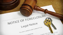 Foreclosure filing sitting on a table with house keys and a gavel
