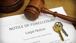 Foreclosure filing sitting on a table with house keys and a gavel Foreclosure filing sitting on a table with house keys and a gavel