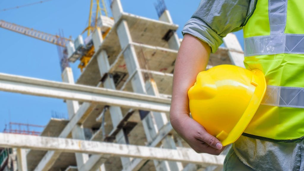 Construction worker holding hard hat, signaling safety on the jobsite