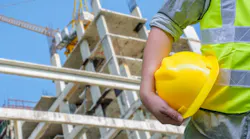 Construction worker holding hard hat, signaling safety on the jobsite