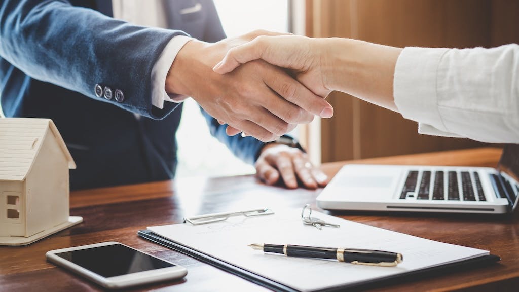 Homebuyer shakes hands with real estate agent after closing on a home
