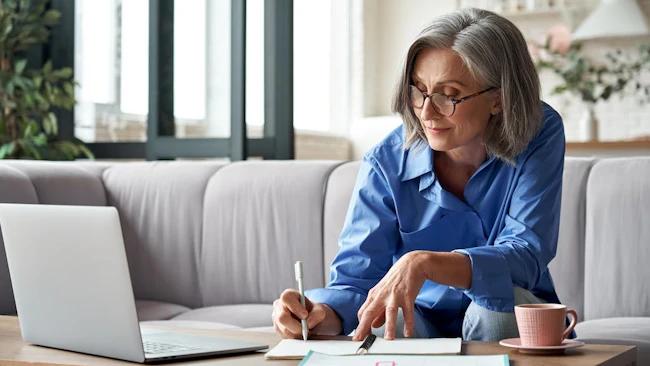 Baby Boomer woman works on laptop at her couch