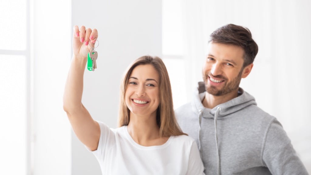 Millennial couple holds up keys to new house