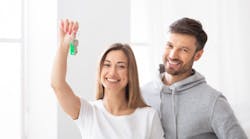 Millennial couple holds up keys to new house Millennial couple holds up keys to new house
