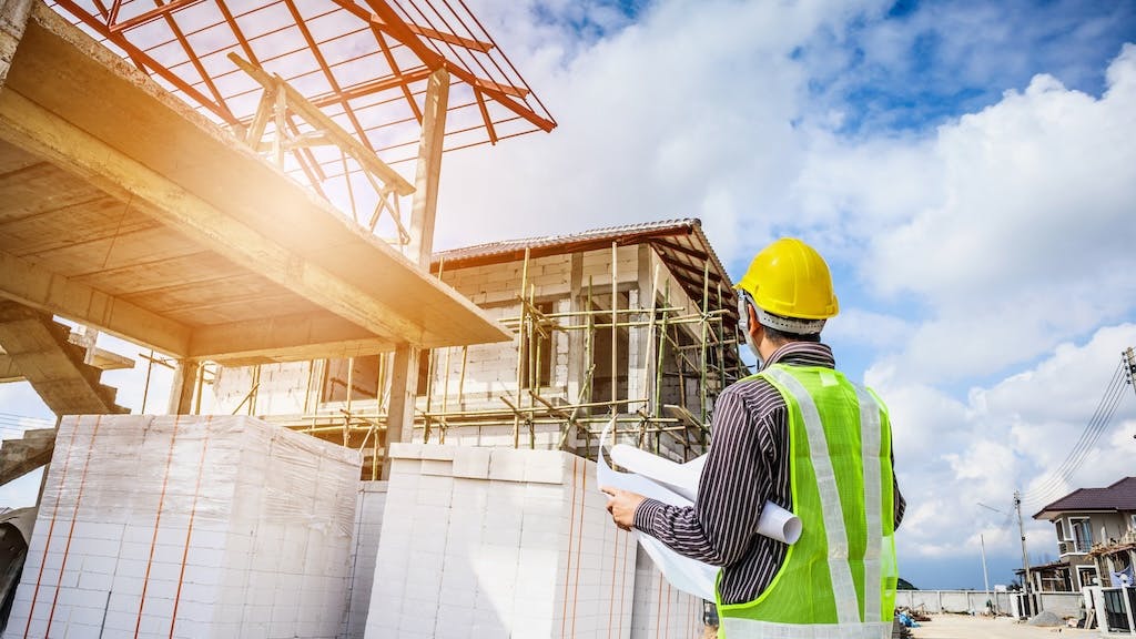 Construction worker stands at a jobsite looking over plans