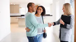 A couple shakes hands with a real estate agent while touring a home