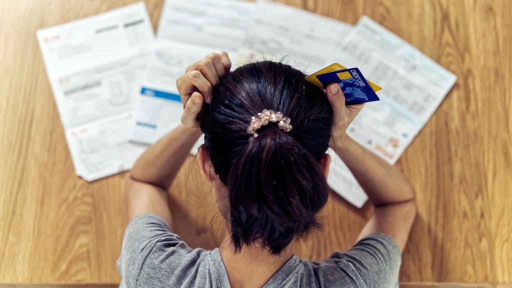 A stressed renter looks over credit card bills
