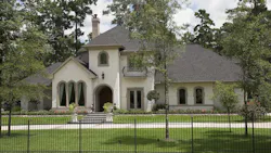 Exterior of gated luxury home surrounded by trees