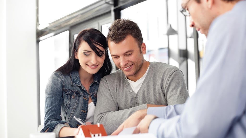 Homebuyers sign papers with a real estate agent