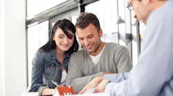 Homebuyers sign papers with a real estate agent