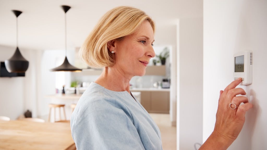 Homeowner adjusting the temperature on a thermostat