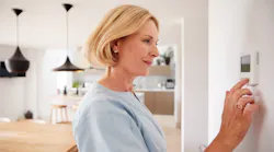 Homeowner adjusting the temperature on a thermostat
