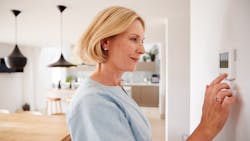 Homeowner adjusting the temperature on a thermostat Homeowner adjusting the temperature on a thermostat