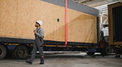 Worker manages loading of factory-built home onto a truck to be transported Worker manages loading of factory-built home onto a truck to be transported
