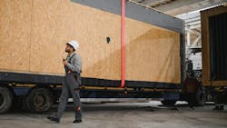 Worker manages loading of factory-built home onto a truck to be transported Worker manages loading of factory-built home onto a truck to be transported