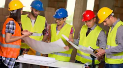 Group of young workers in safety vests and hard hats working together