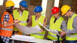 Group of young workers in safety vests and hard hats working together Group of young workers in safety vests and hard hats working together