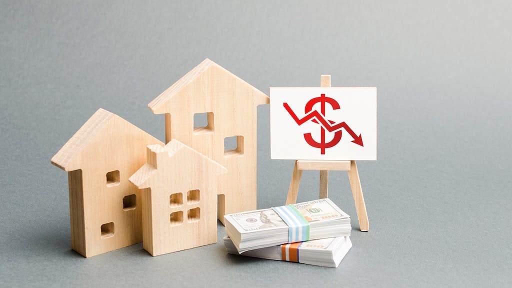 Model home sitting next to small pile of cash, indicating falling home equity