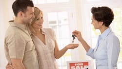 Real estate agent hands buyers a set of keys Real estate agent hands buyers a set of keys