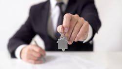 Investor holds up a house key Investor holds up a house key