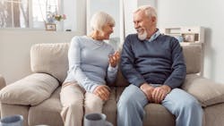 Baby Boomer couple sitting on a couch, talking at the home they rent Baby Boomer couple sitting on a couch, talking at the home they rent