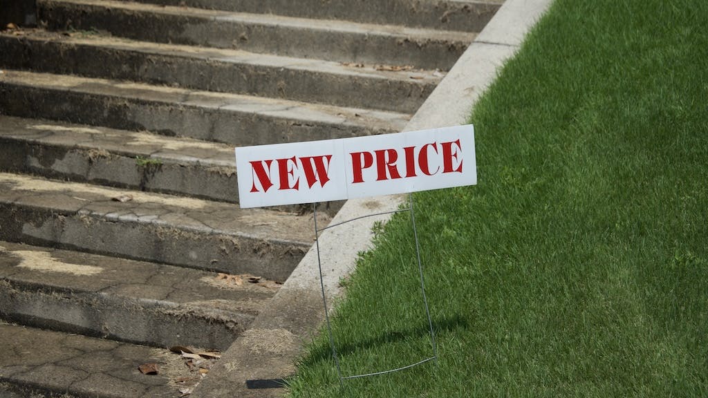 House with 'new price' sign in front yard