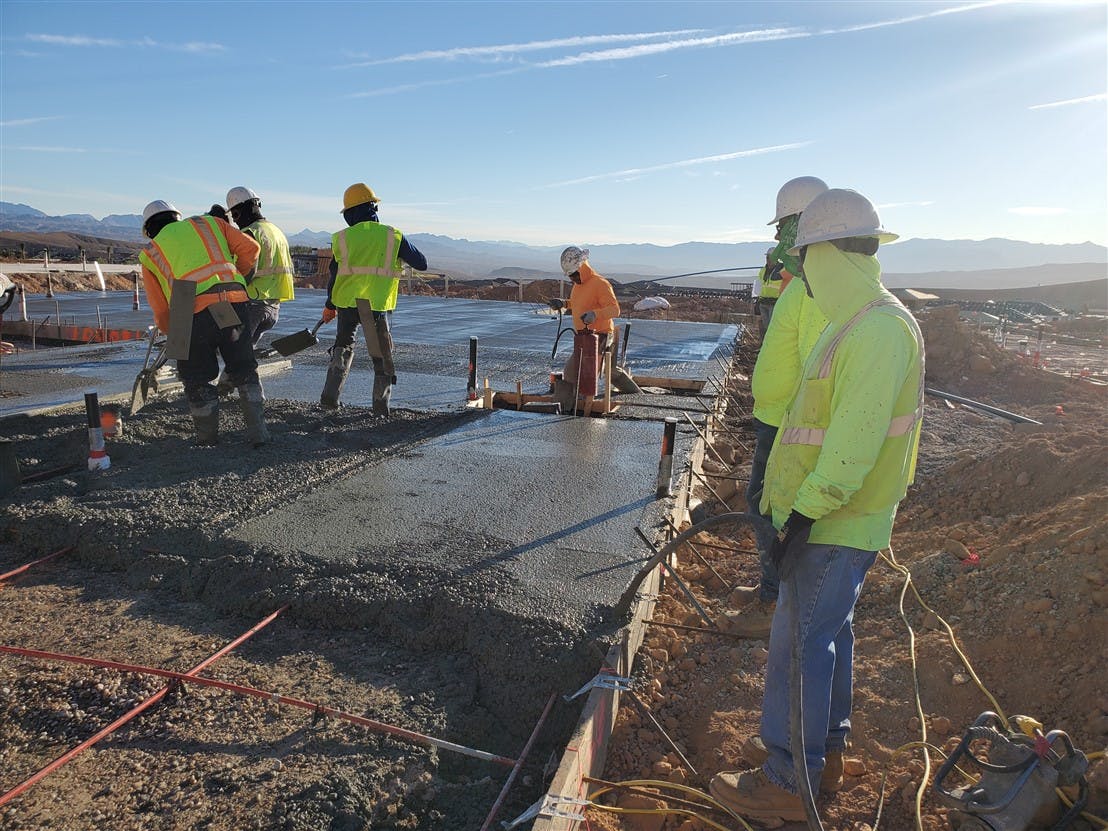 A concrete foundation and slab being properly consolidated by means of vibration, with an adequate number of workers on site to place and finish the pour.