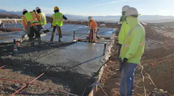 A concrete foundation and slab being properly consolidated by means of vibration, with an adequate number of workers on site to place and finish the pour.