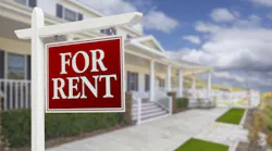 A 'For Rent' sign in front of a single-family home