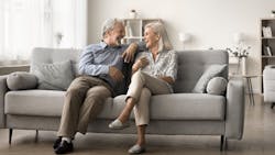 Older couple sitting on a couch in their home Older couple sitting on a couch in their home