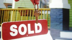 Homeowner holding house keys in front of a 'Sold' sign Homeowner holding house keys in front of a 'Sold' sign
