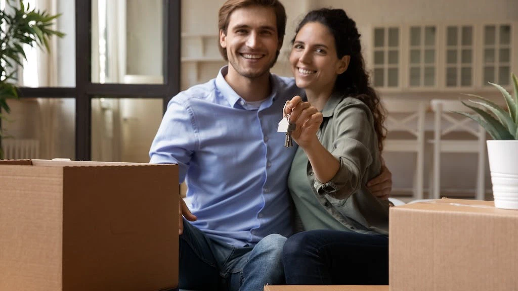 Millennial couple sitting near moving boxes in their new home