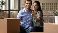 Millennial couple sitting near moving boxes in their new home Millennial couple sitting near moving boxes in their new home